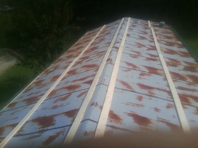 Rusted metal roof panels with new wood purlins before replacement — Storm Damage Roof Repair in Bloomington by Roofing Brothers