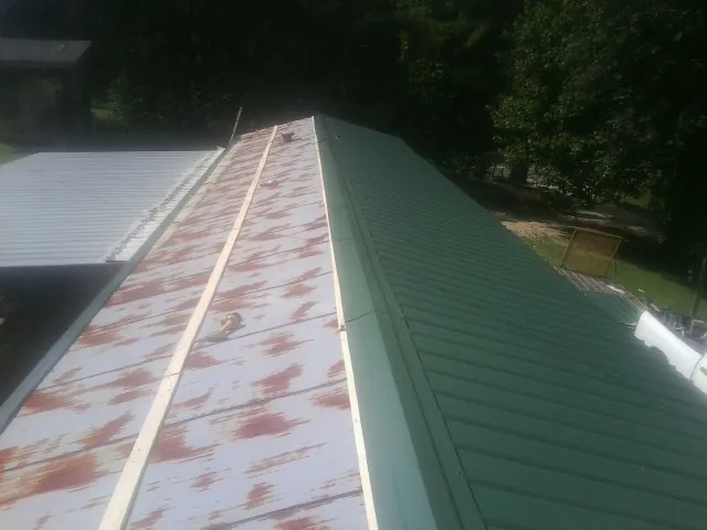 Old rusted panels beside newly installed green metal roofing — Wind Damage Roof Repair by Roofing Brothers in Bloomington