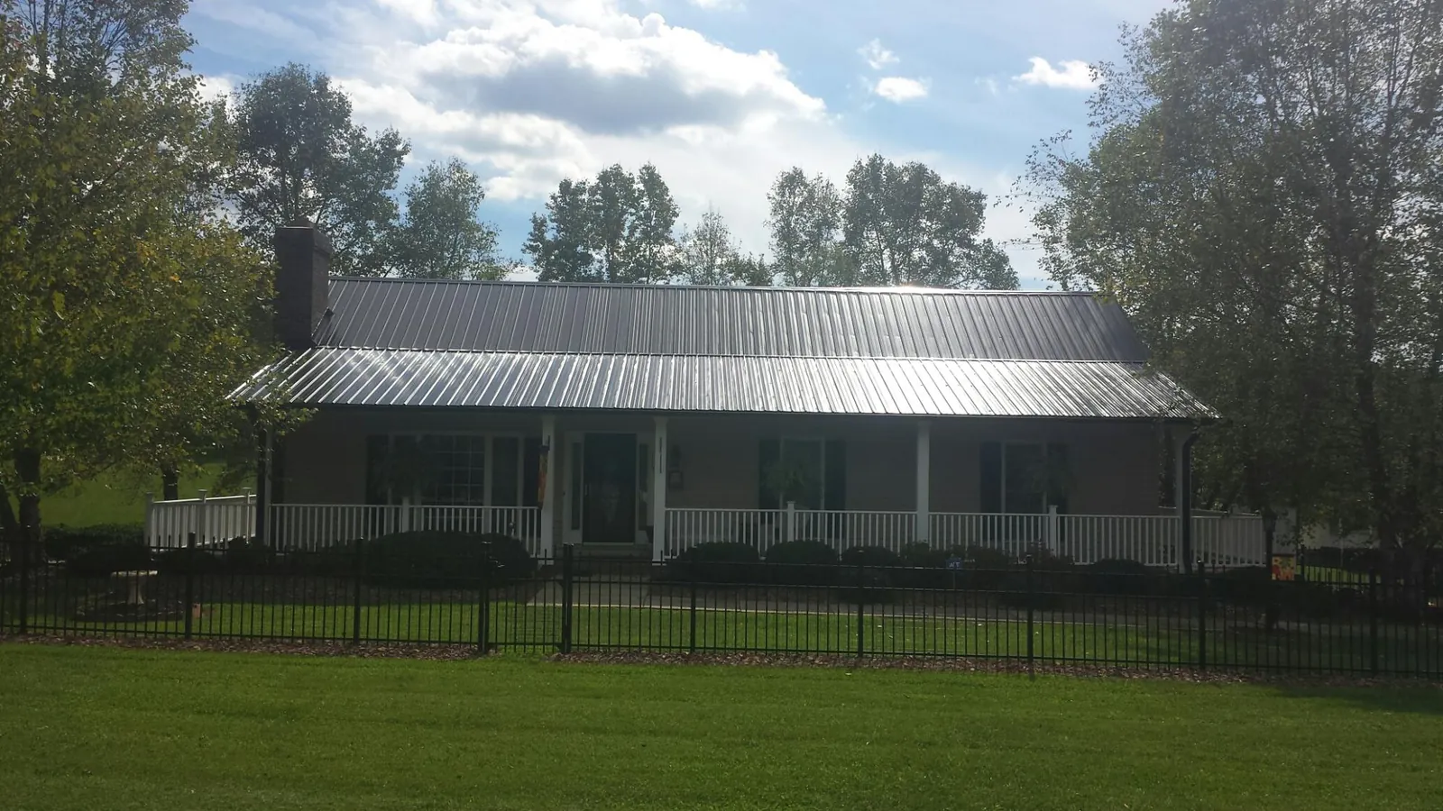 Gray metal roof on a brick ranch with a full width front porch — Gutter Guard Installation work by our crew in Bloomington